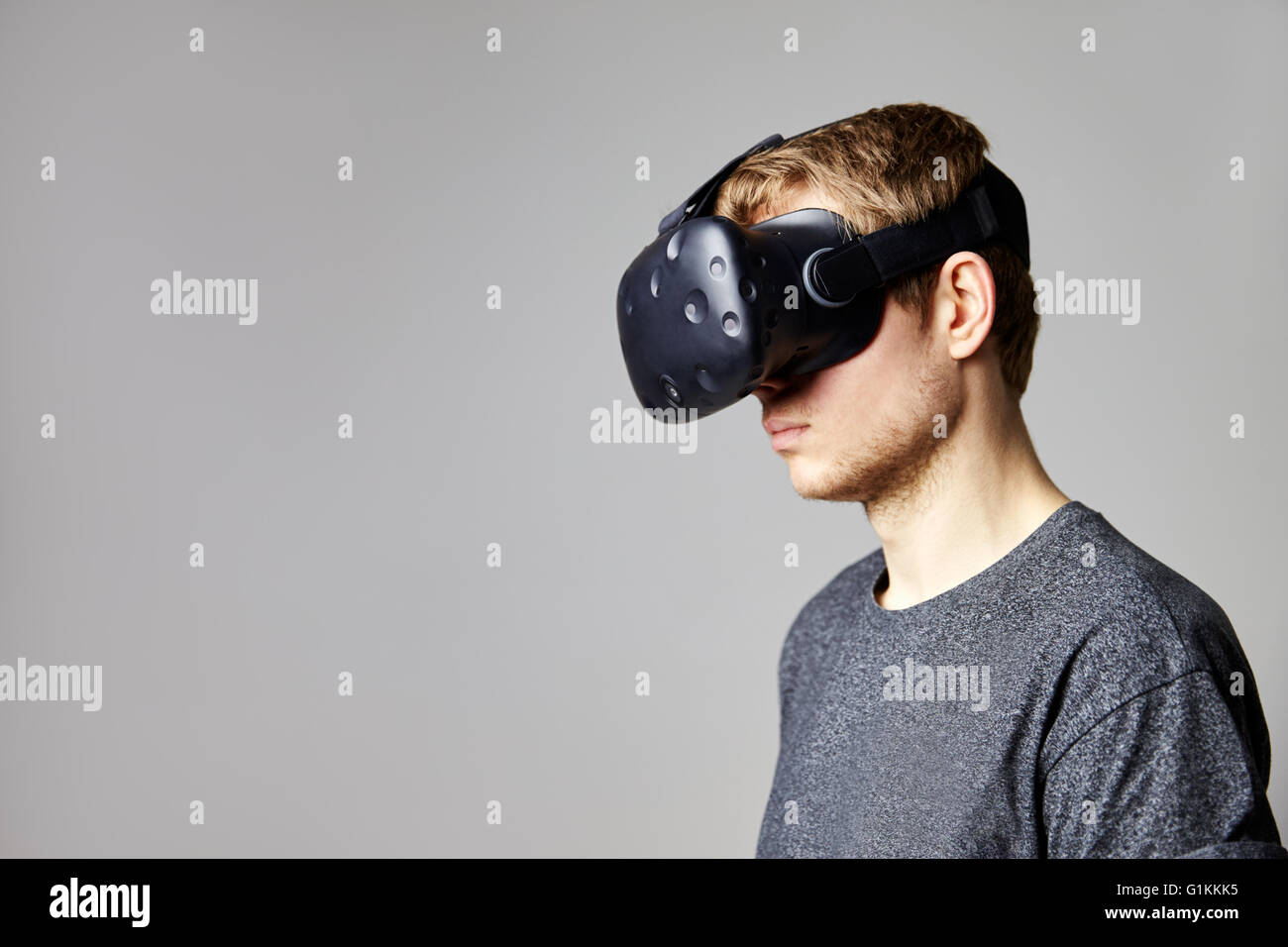 Hombre sentado en el sofá en casa vistiendo casco de realidad virtual Foto de stock