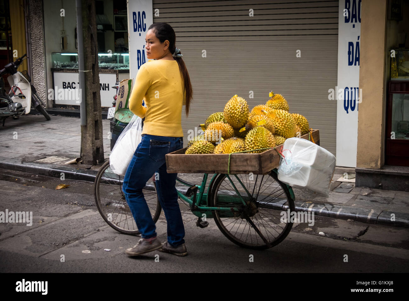 Una señora que vende fruta durián desde su bicicleta en el barrio antiguo de Hanoi. Foto de stock