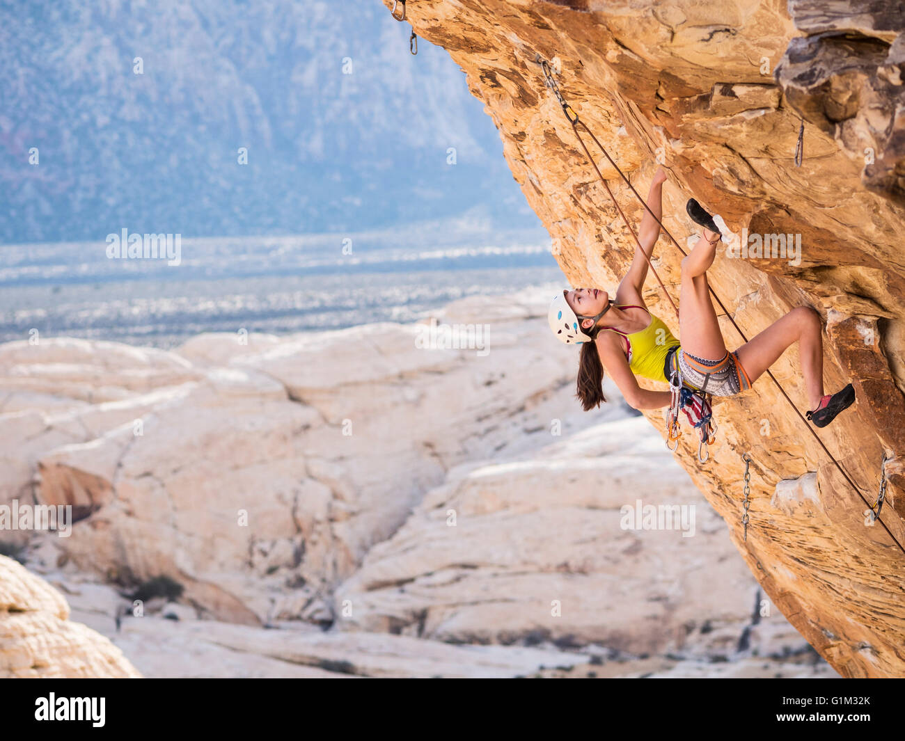 Niña de raza mixta escalada en roca sobre un acantilado Foto de stock