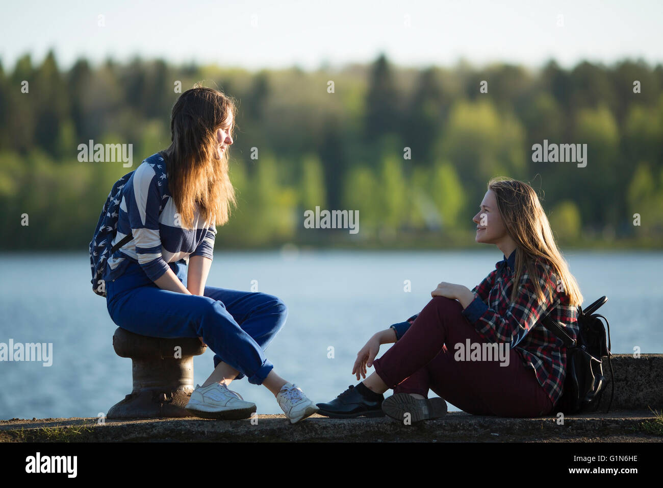 Dos amigos adolescentes pasan tiempo juntos en el malecón del río. Foto de stock