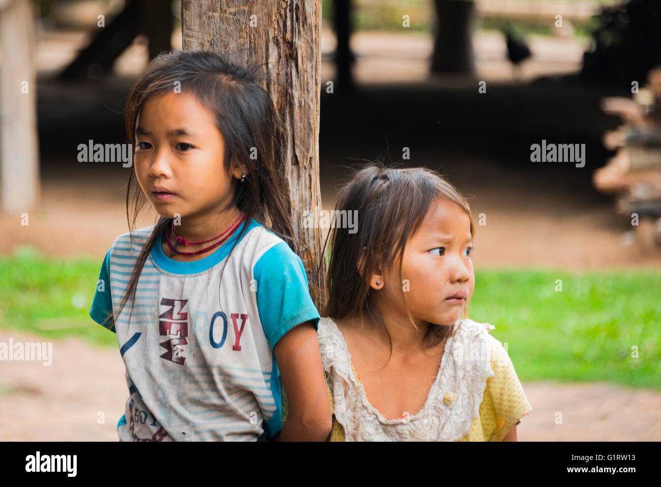 Dos chicas tímidas por un poste de una choza, Ban Nalan Tai, minoría khmu Village, el Parque Nacional de Nam Ha, Luang Namtha, Laos Foto de stock