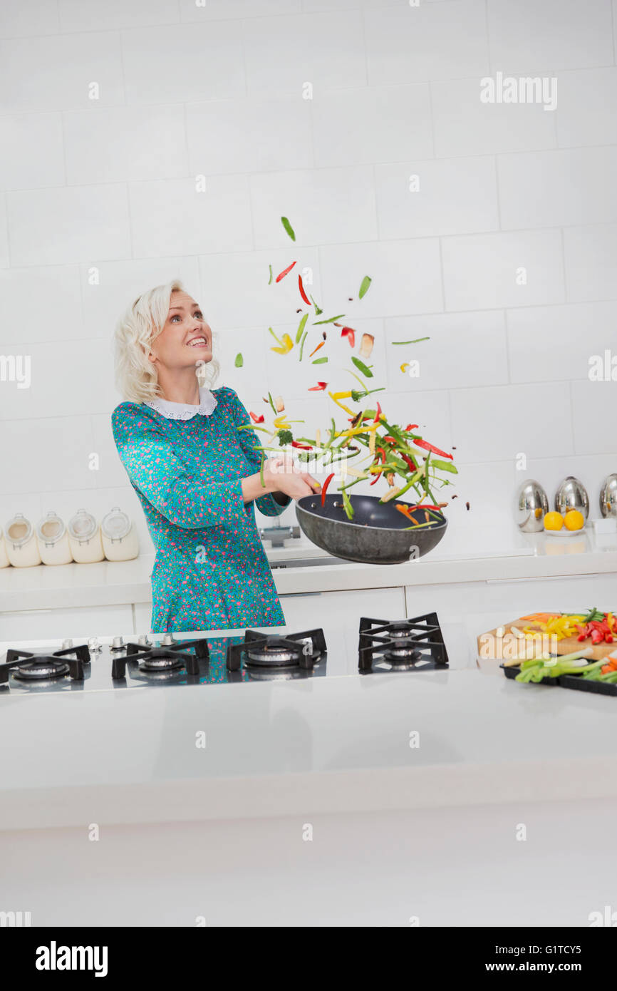 Mujer cociendo voltear las verduras en la sartén en la cocina Foto de stock