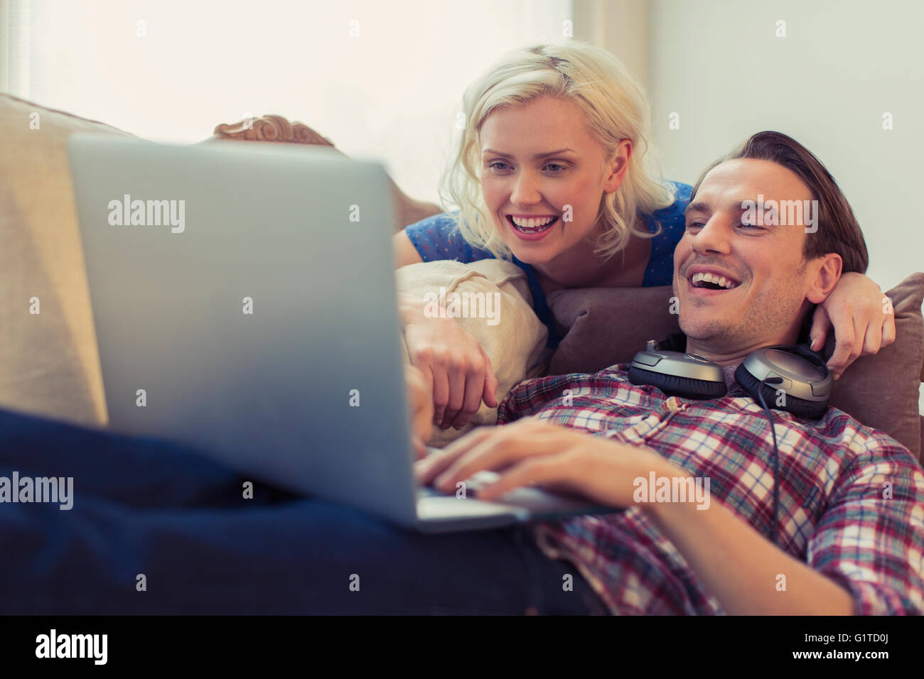 Sonriente pareja utilizando el portátil en el sofá de la sala Foto de stock