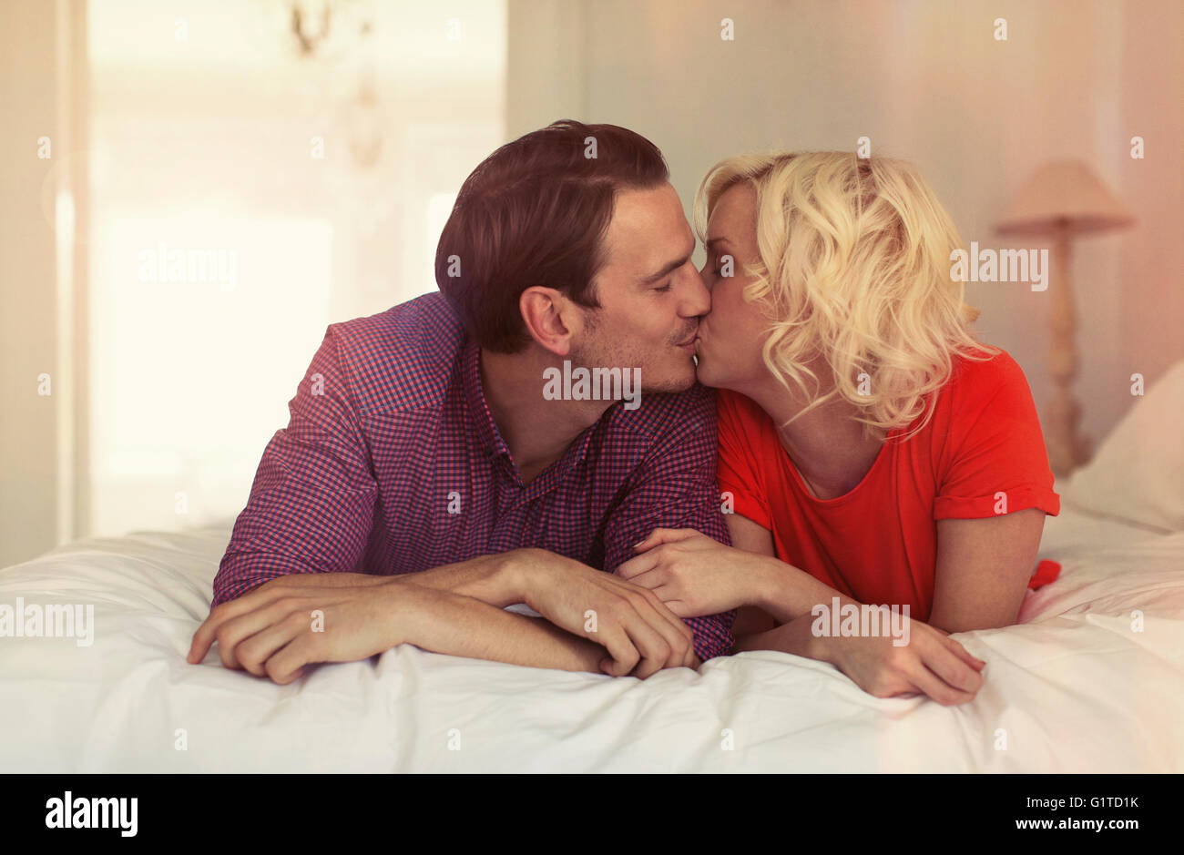 Pareja besándose en la cama Foto de stock