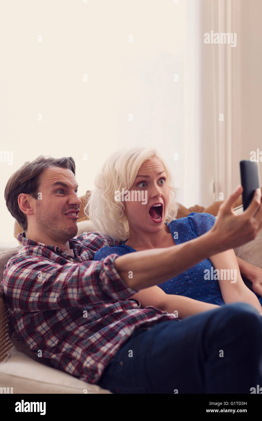 Juguetón pareja haciendo caras teniendo selfie Foto de stock