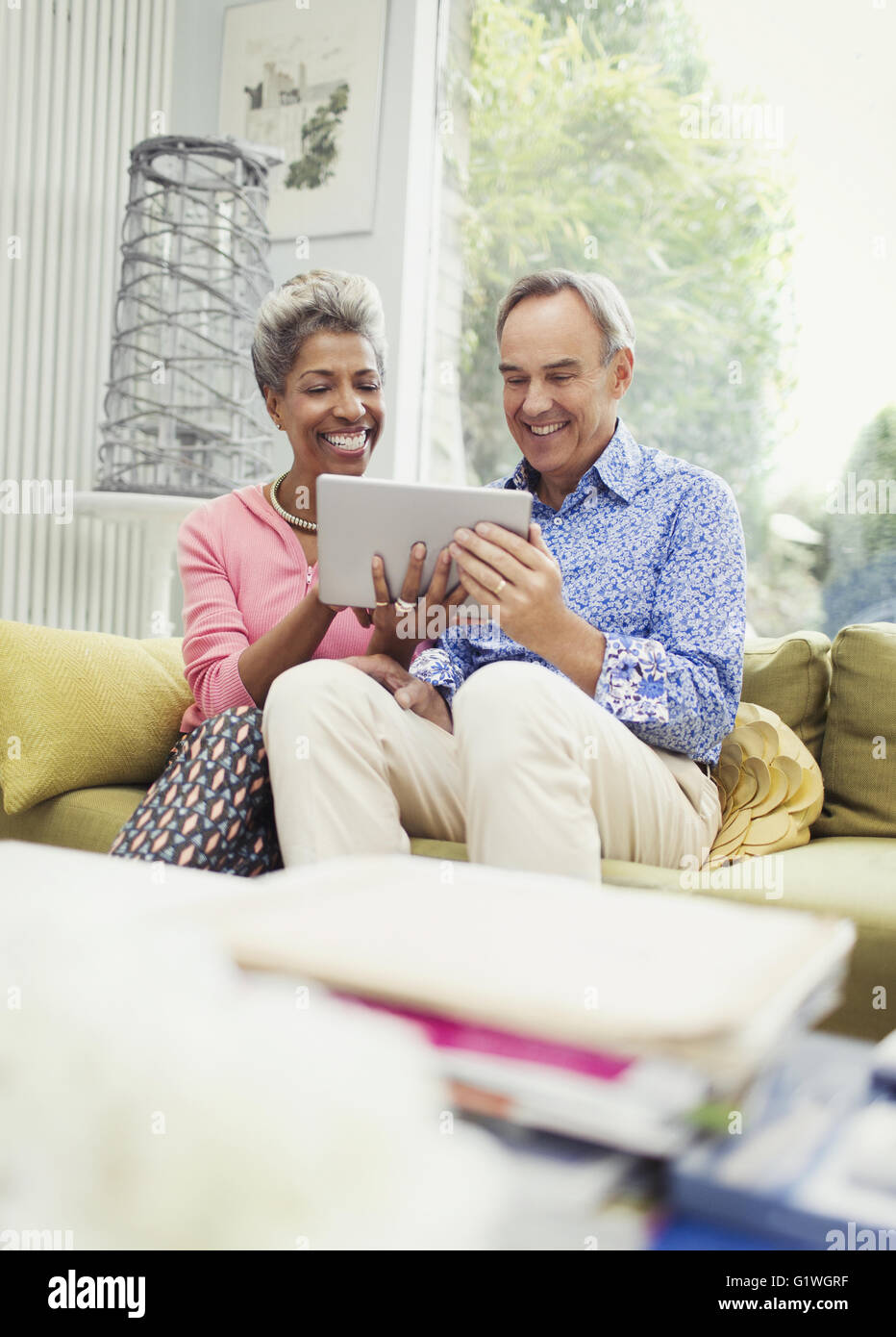 Sonriente pareja compartiendo tableta digital en el sofá de la sala Foto de stock