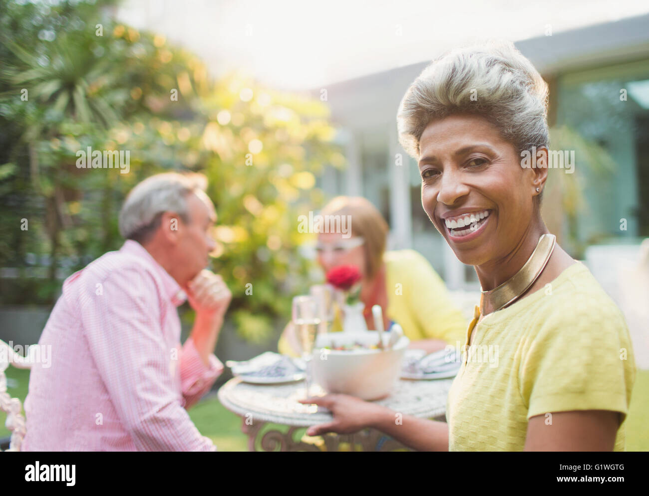 Retrato sonriente mujer madura disfrutando del almuerzo con amigos en el jardín Foto de stock