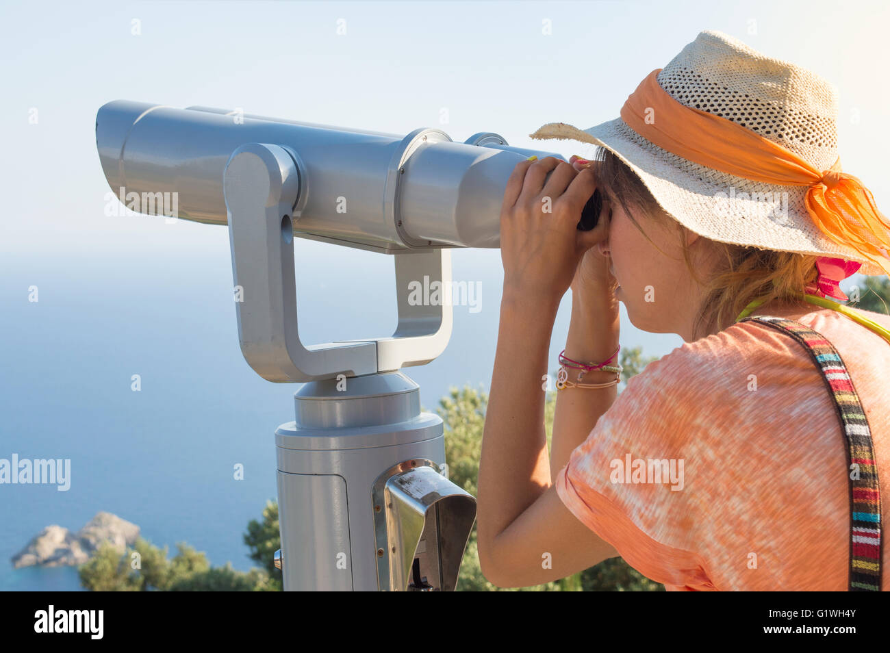 Mujer joven mirando a través de binoculares de público en el horizonte. Vacaciones de verano Foto de stock