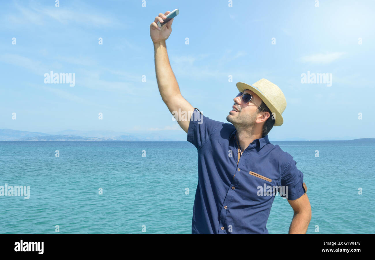 Hombre teniendo un Selfie con su teléfono inteligente en la playa Foto de stock