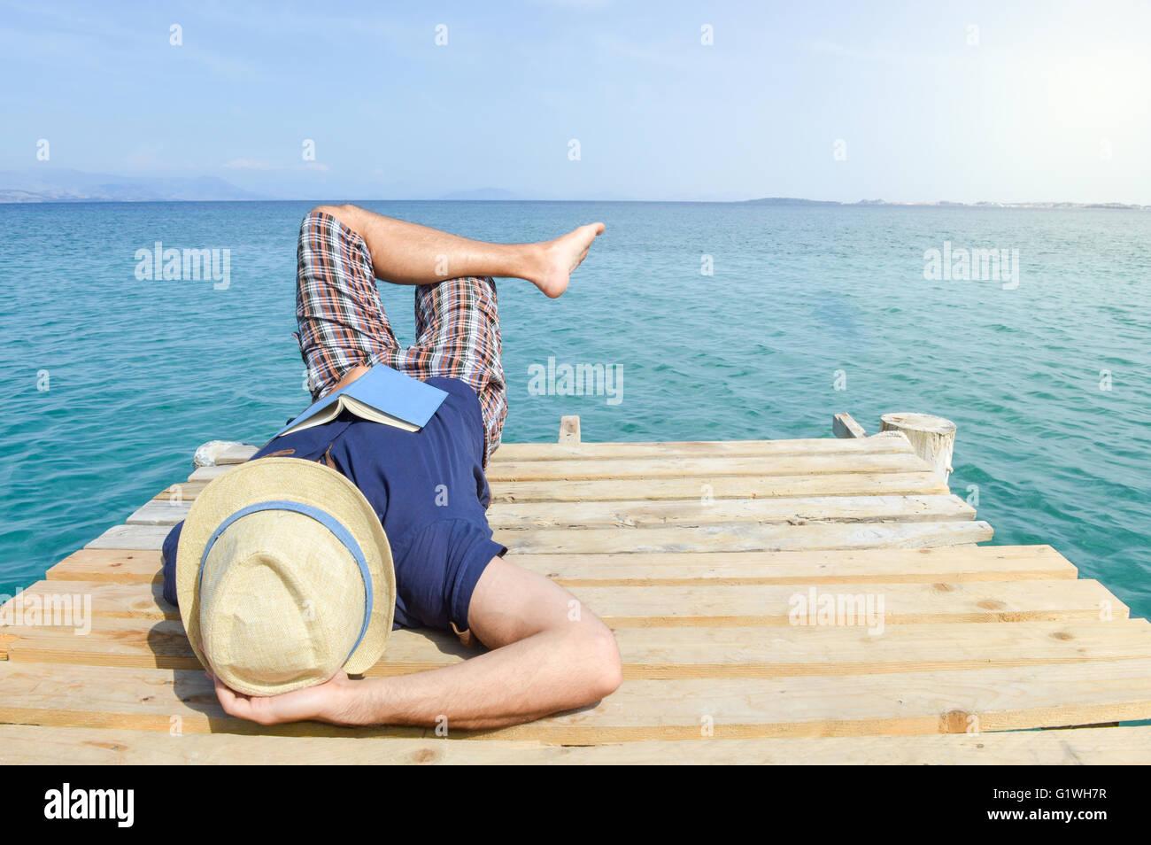 Hombre tumbado en el dock con un libro. Vacaciones de verano la relajación Foto de stock
