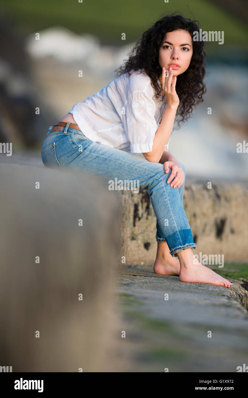 Un descalzo barefoot joven mujer morena delgada atractiva chica en la  reflexión profunda, sentado por sí solos , afuera afuera en las noches  cálidas. UK Fotografía de stock - Alamy