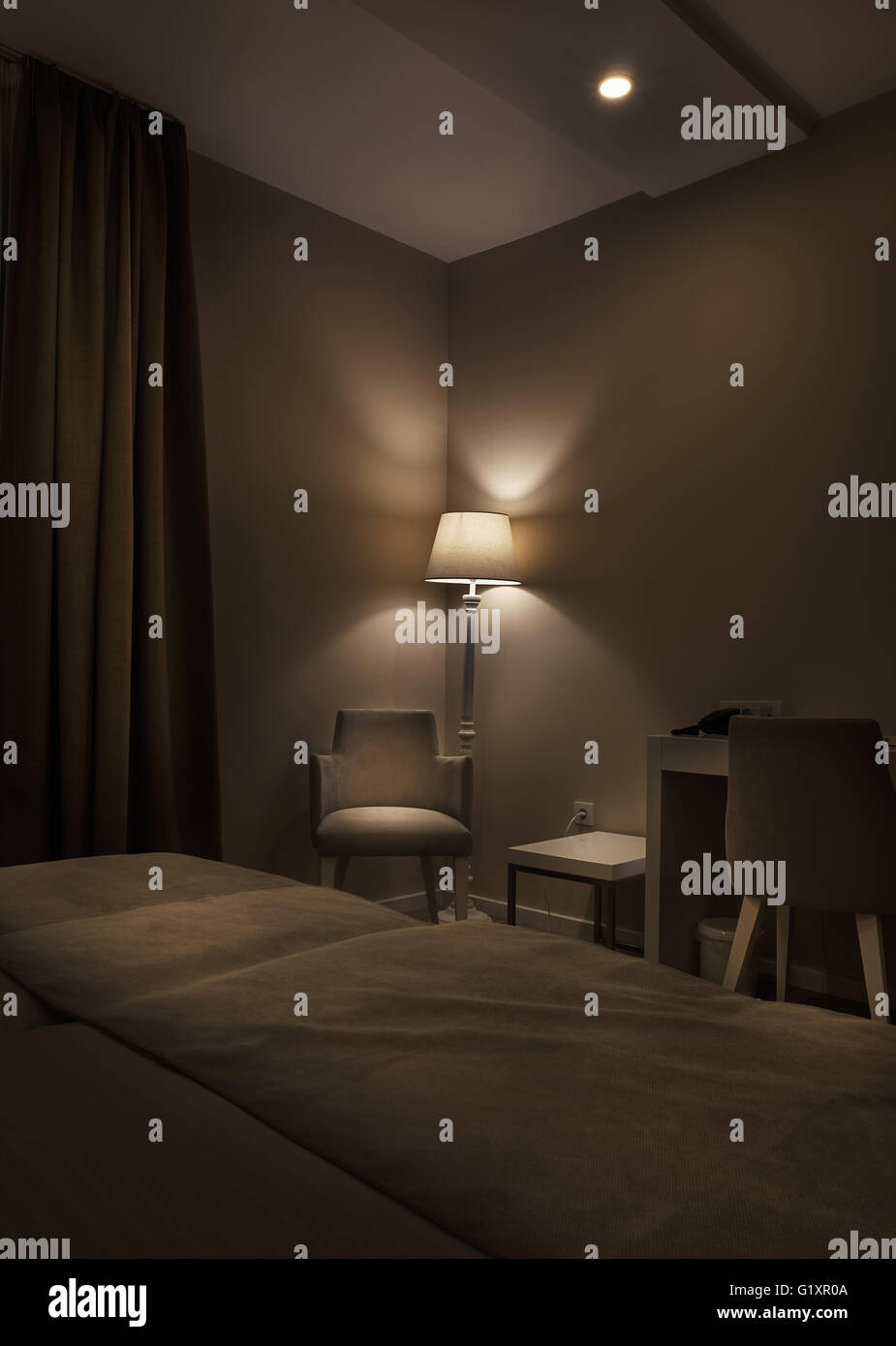 Detalles de la habitación de un hotel, y un sillón, lámparas retro grandes cortinas de color marrón oscuro, ambiente tranquilo durante la noche. Foto de stock