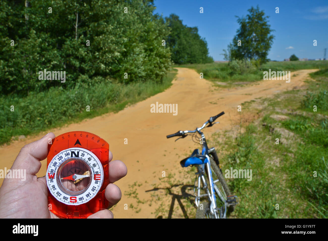 Con una brújula y horquilla delantera de una bicicleta. Orientación durante un paseo en bicicleta en las zonas rurales. Foto de stock