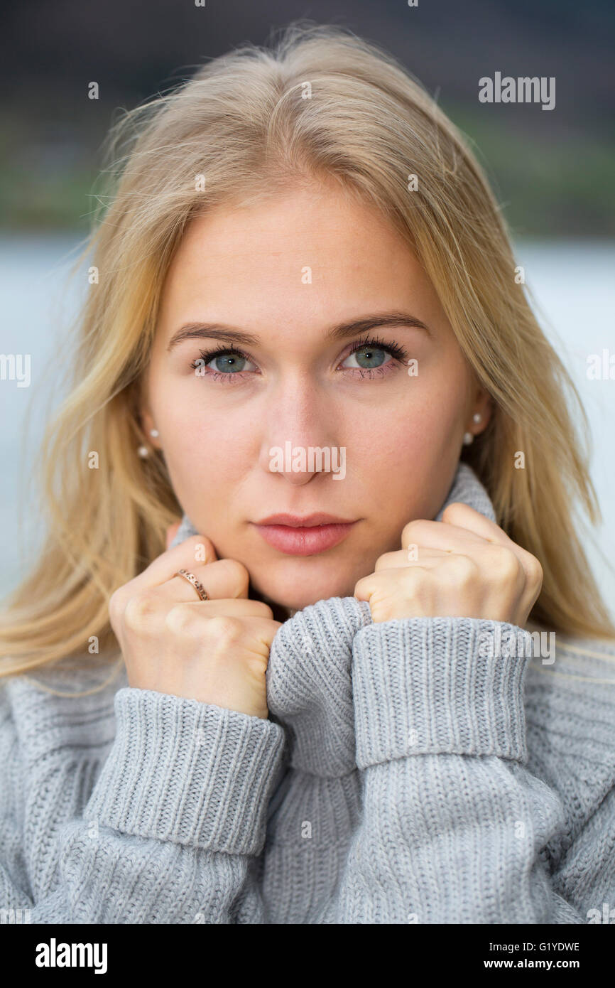 Retrato de una mujer joven con largo pelo rubio y suéter caliente Foto de stock