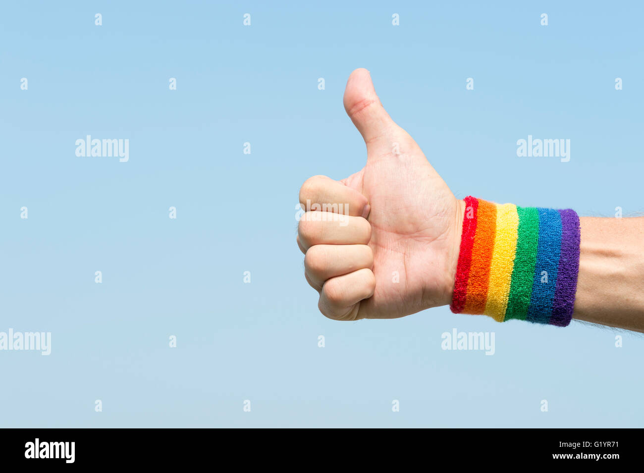 La mano del atleta dando pulgares para arriba con los colores del arco iris  del orgullo gay Muñequera contra el cielo azul brillante Fotografía de  stock - Alamy