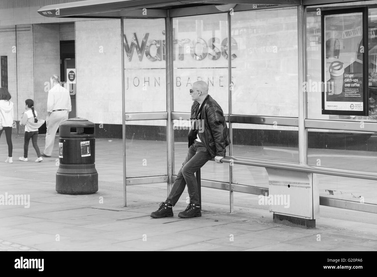 Hombre sentado en un banco en una parada de autobús en Londres alojamiento Foto de stock