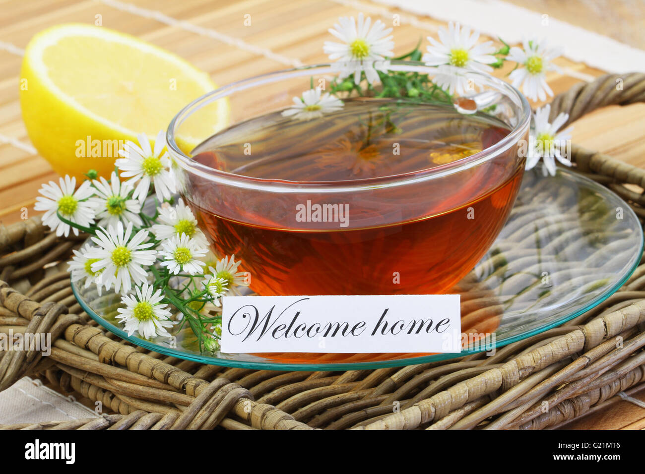 Tarjeta de bienvenida a casa con una taza de té de manzanilla con frescas flores de manzanilla y