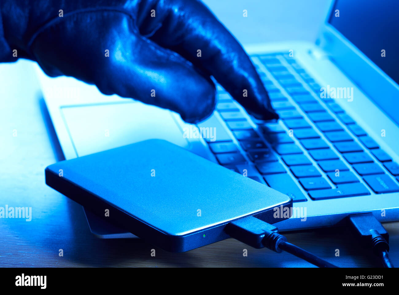 Criminales cibernéticos descargando datos en un disco duro portátil Foto de stock
