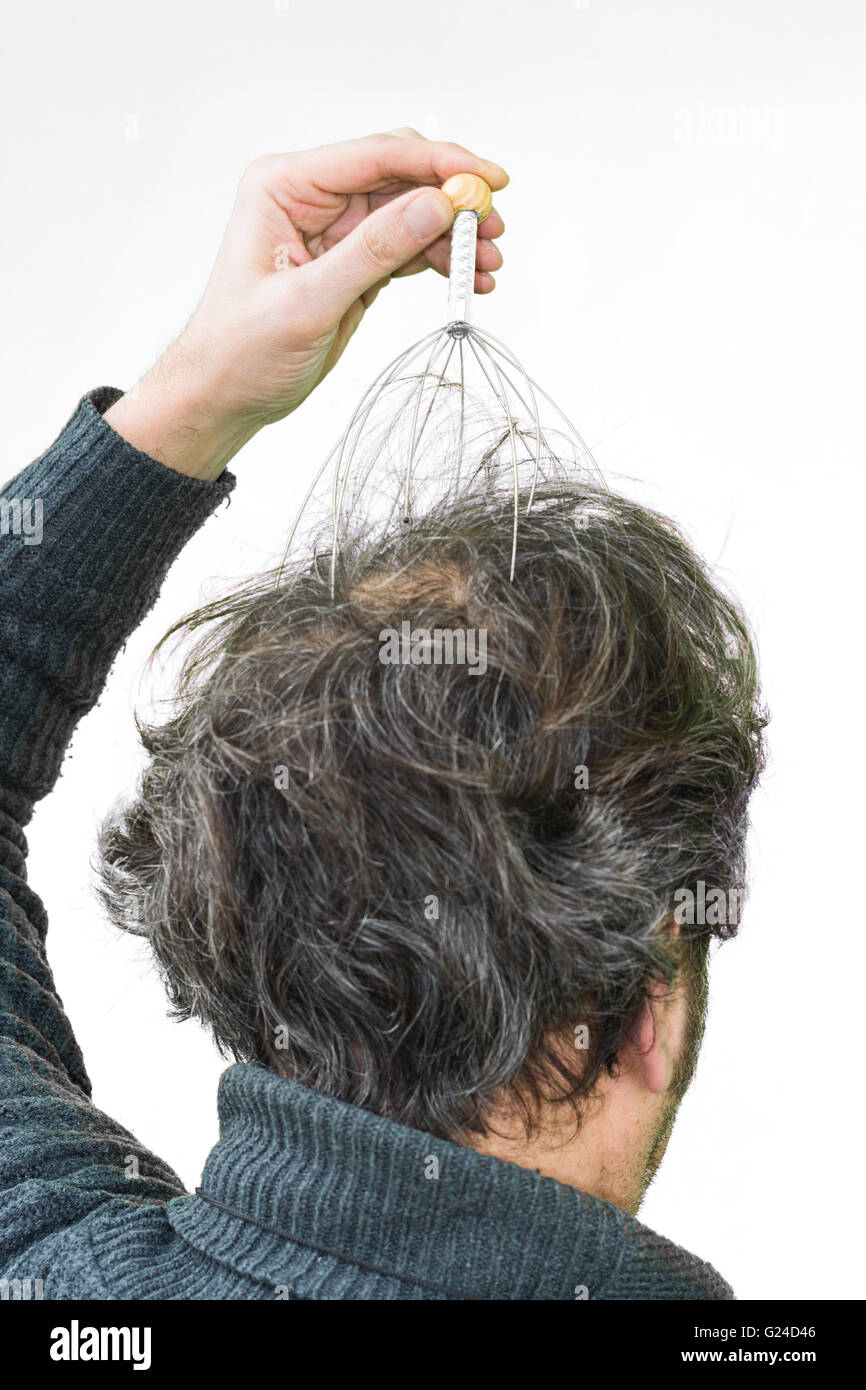 El hombre se relaja con el genio cabeza masajeador. Terapia alternativa. Masaje indio de cabeza herramienta, auto cabeza masajeador. Foto de stock