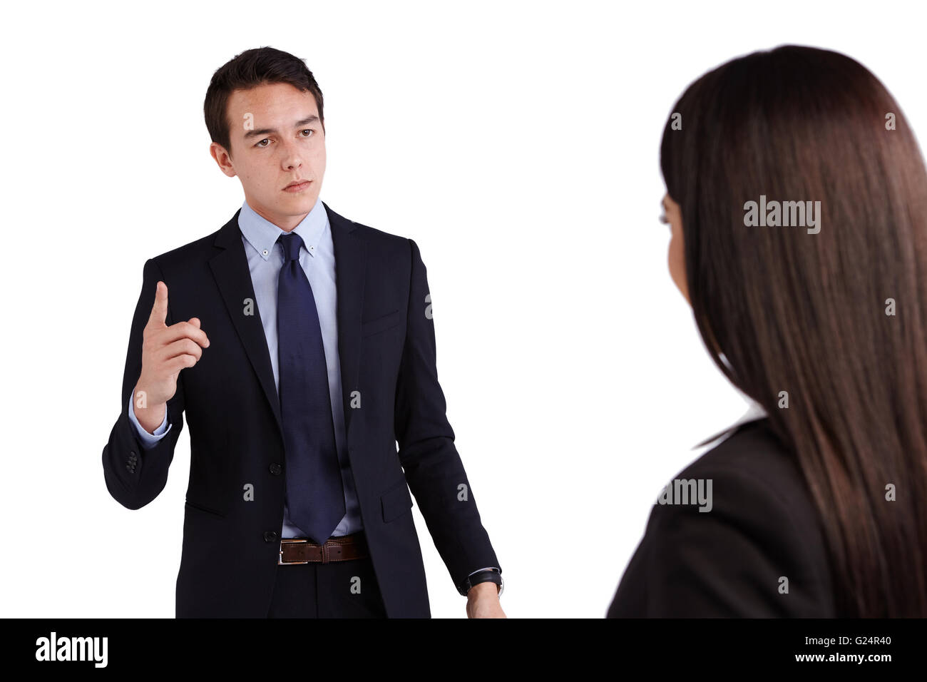 Un joven hombre caucásico es reprender a una mujer de negocios. Él es frowining y con enojo. Foto de stock