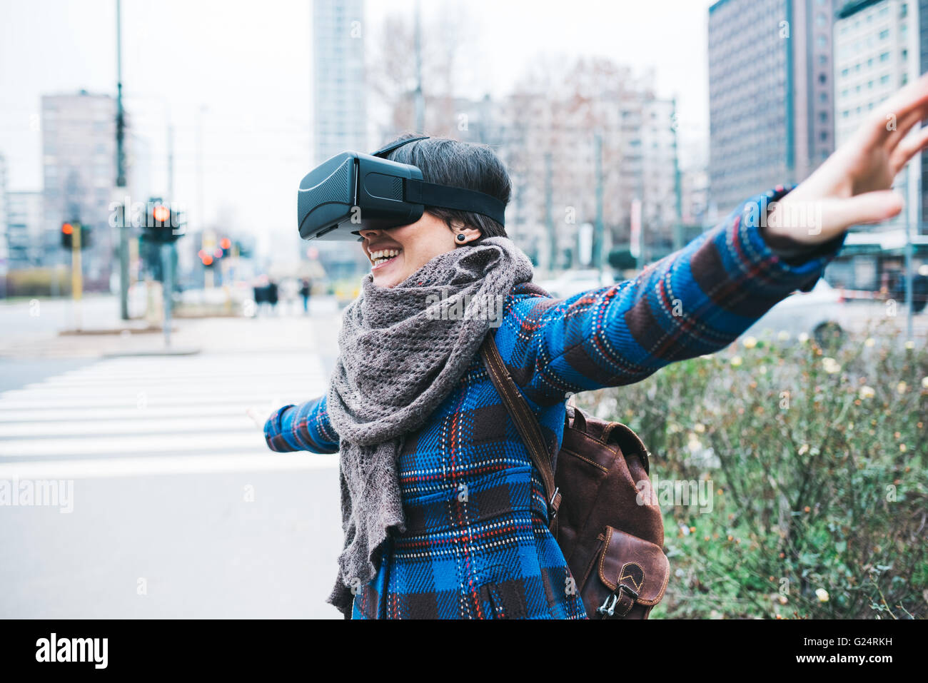 Apuesto joven mujer caucásica con visor 3D al aire libre en la ciudad sonriendo con los brazos abiertos - la felicidad, futurista, concepto tecnológico Foto de stock