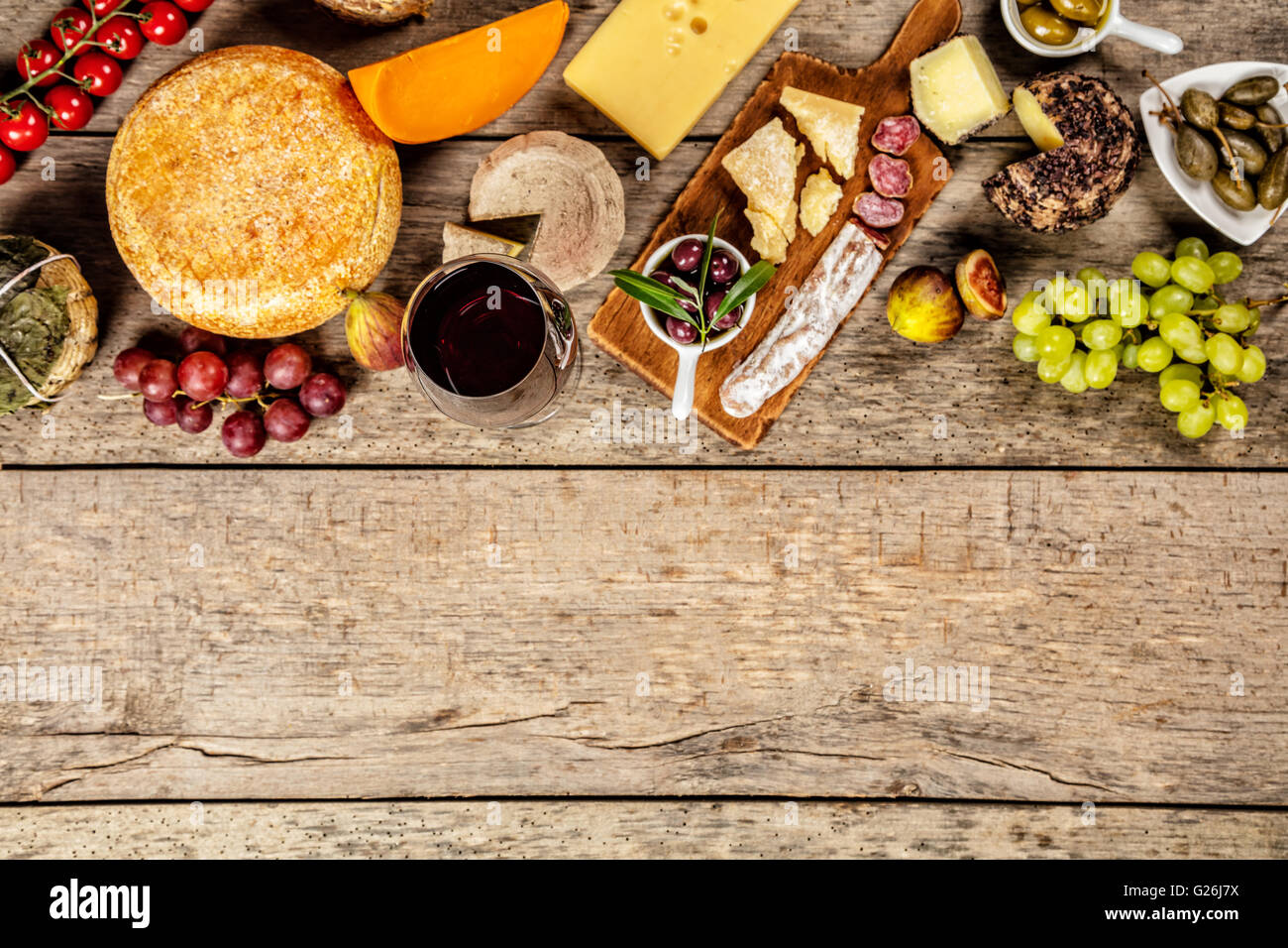 Diversos tipos de queso tradicional y la delicadeza adecuada para el vino, colocados sobre madera, disparado desde un alto ángulo de visualización. Foto de stock
