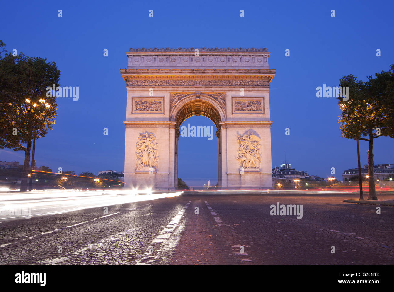 Vista frontal del Arc de Triomphe (Arco de Triunfo) en París al anochecer con semáforo trail Foto de stock