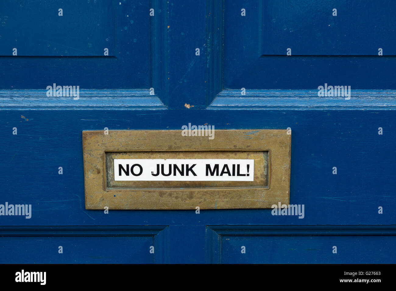 "No correo basura" pegatina en latón letterbox en puerta delantera pintada de azul Foto de stock