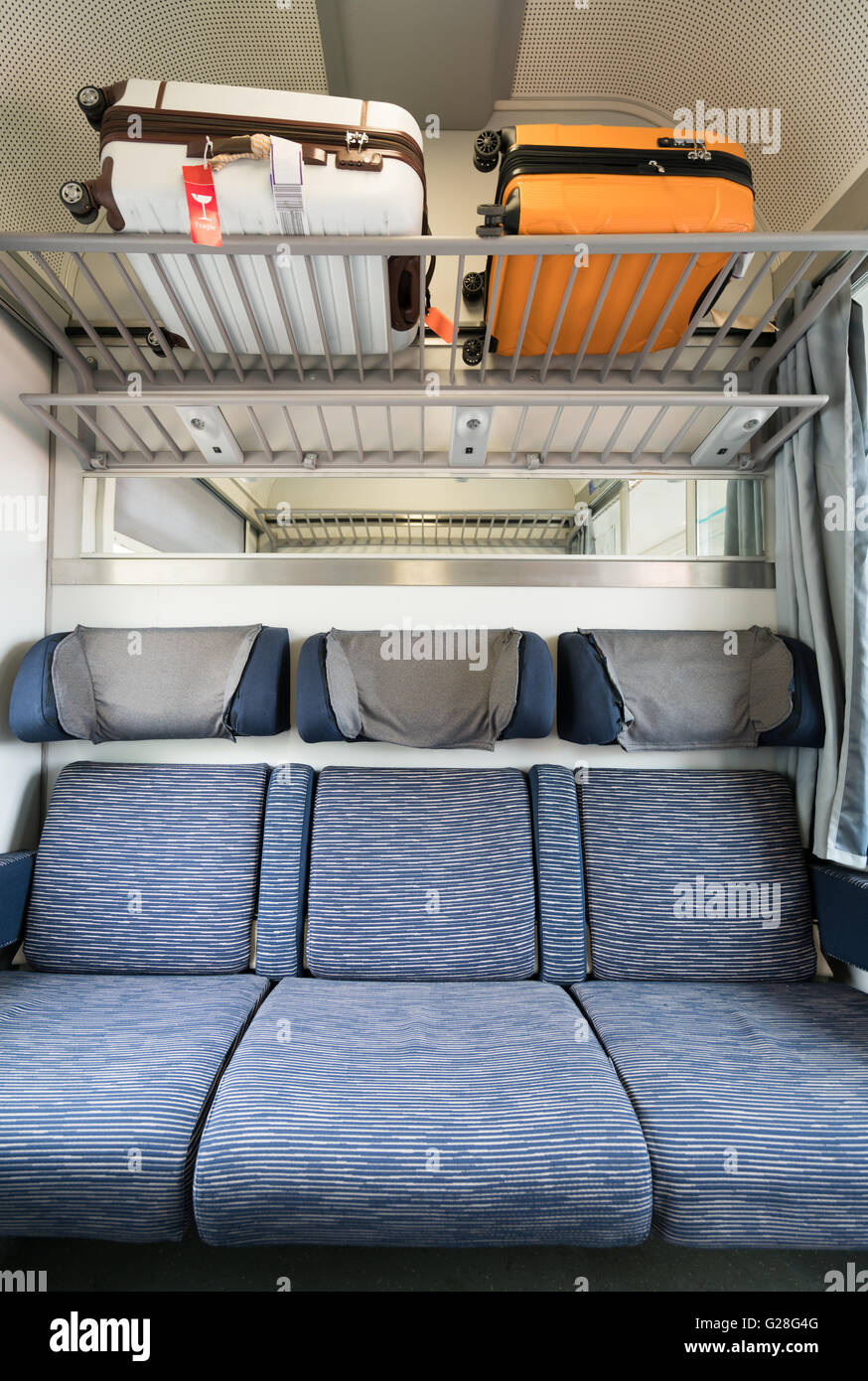 Tres asientos vacíos adyacentes en tren europeo moderno con el equipaje en la parte superior, orientación vertical Foto de stock