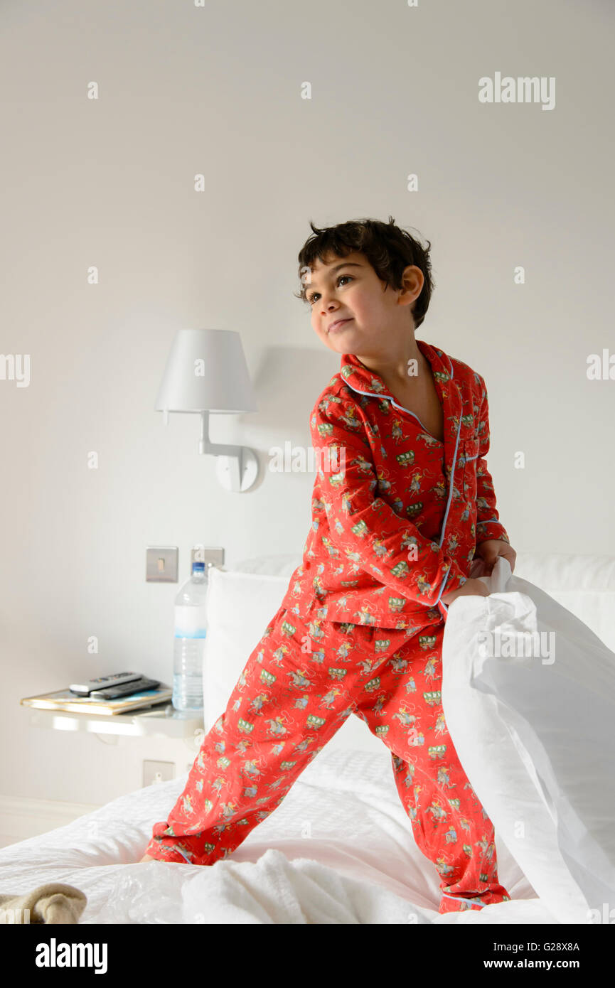 Niño jugando en la cama en pijama Foto de stock