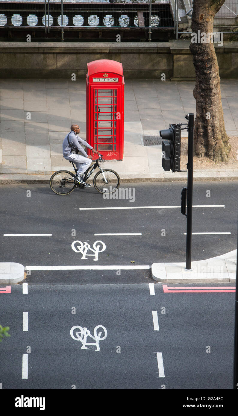 Una vista aérea de un ciclista en un carril de bicicletas pasando un cuadro Teléfono rojo ciclo withtwo signos en el terraplén en Londres Foto de stock
