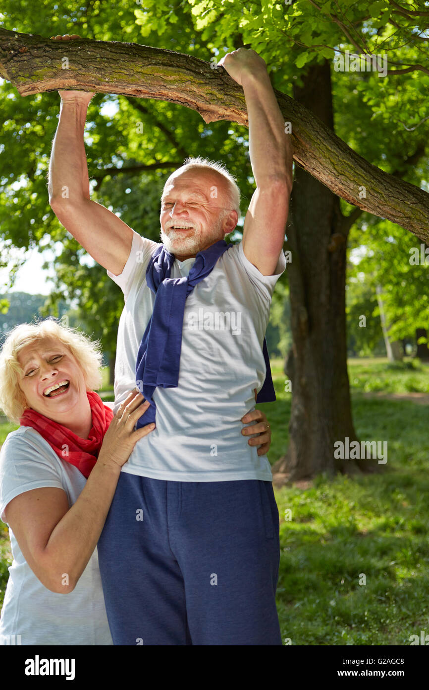 Viejo haciendo pull-ups en un árbol en un parque de verano Foto de stock