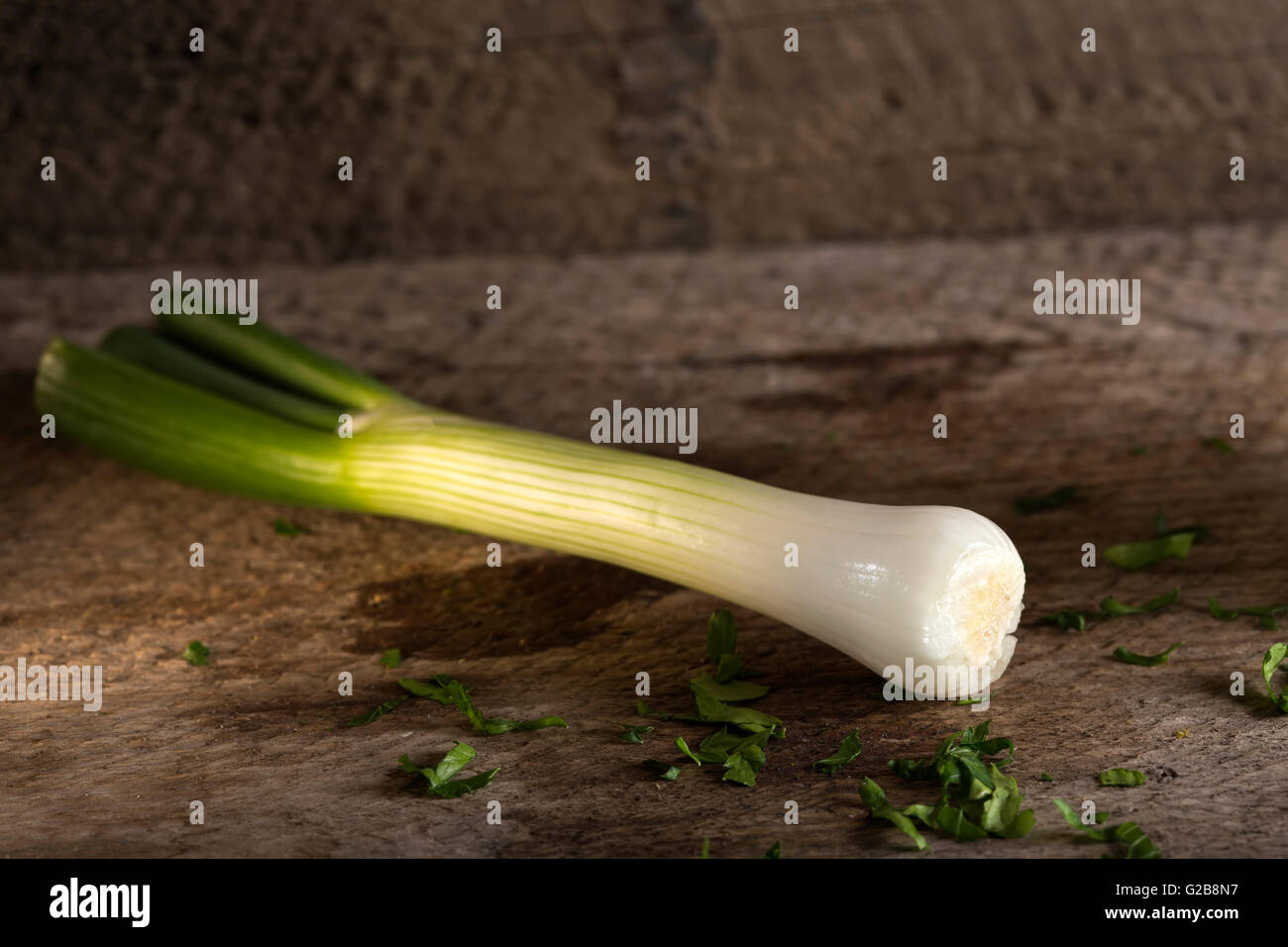 Una cebolleta, también conocida como ensalada de cebolla, cebolleta o cebollino sobre fondo de madera Foto de stock