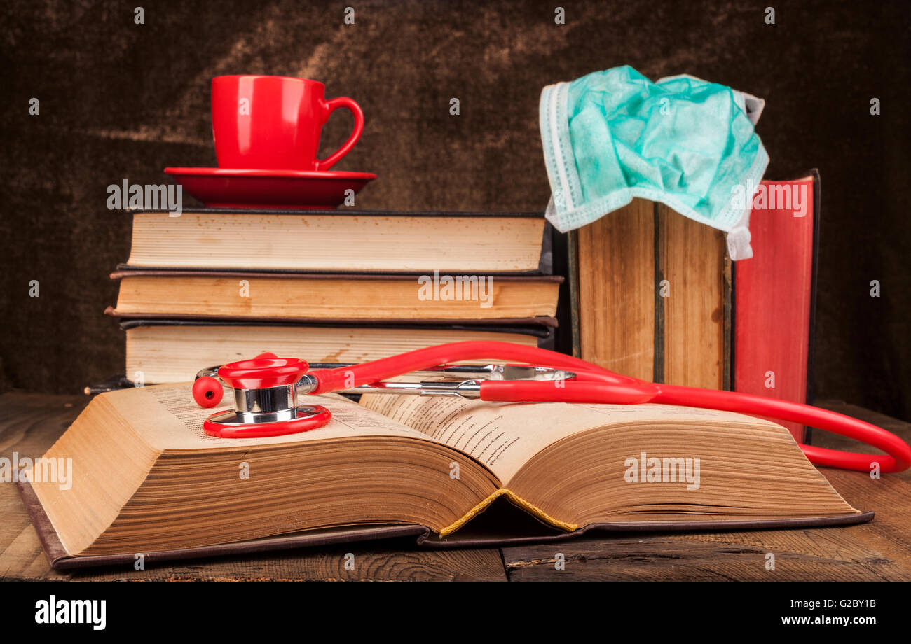 Libros antiguos sobre la mesa de madera con café y rojo estetoscopio en Libro abierto Foto de stock