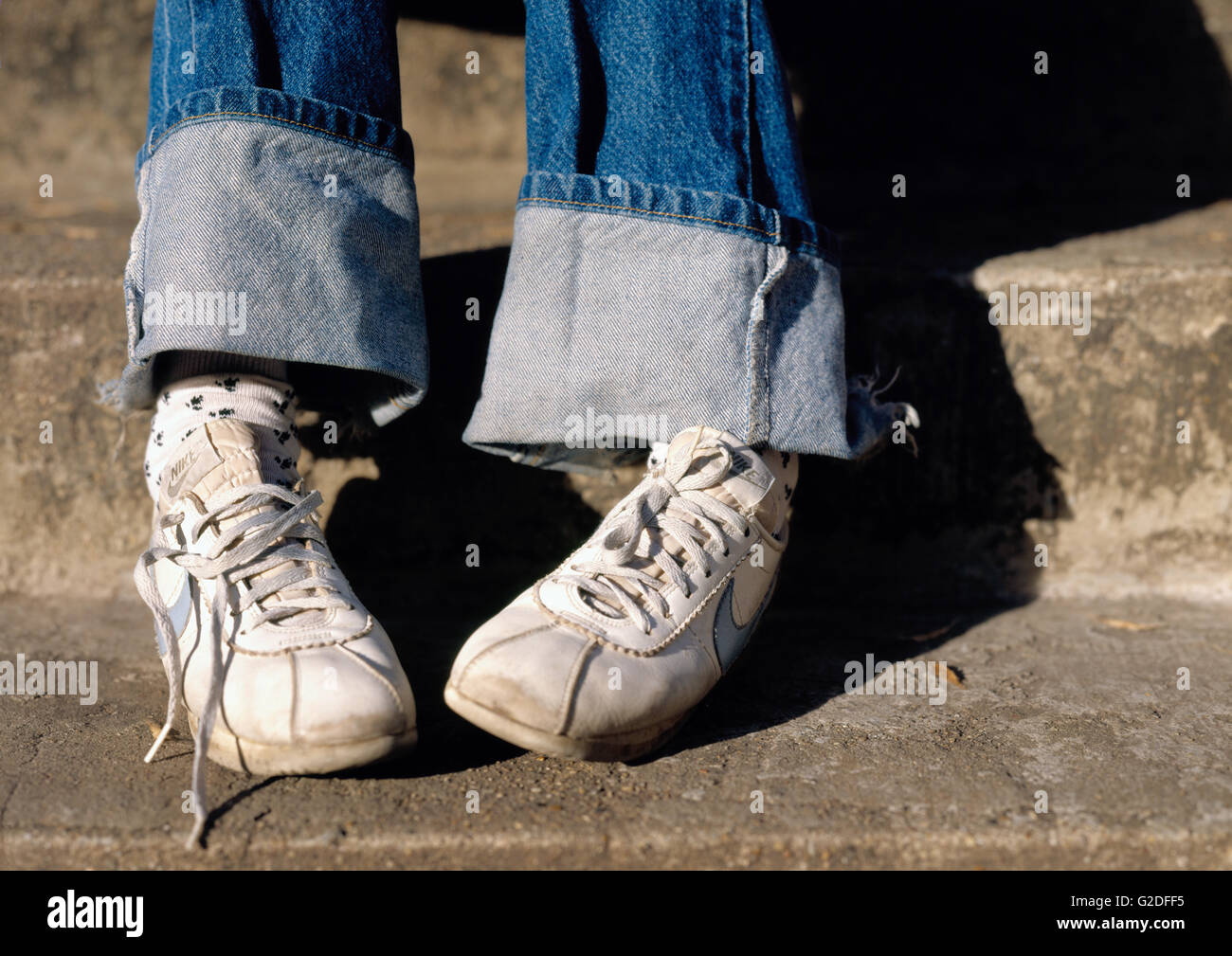 Zapatillas de chica sentada en pasos de exterior Foto de stock