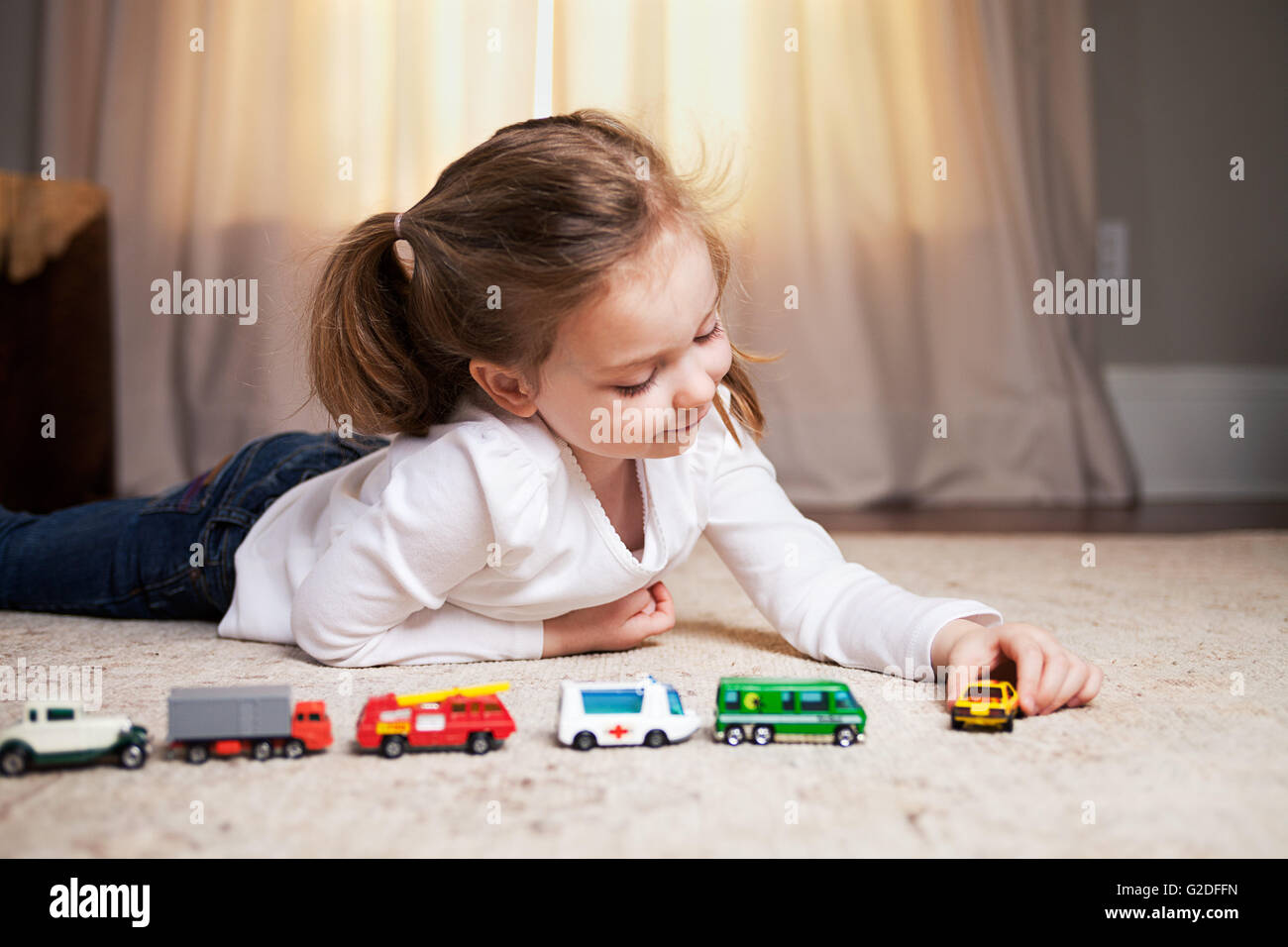 Niña jugando en el piso con coches y camiones en miniatura Fotografía de  stock - Alamy