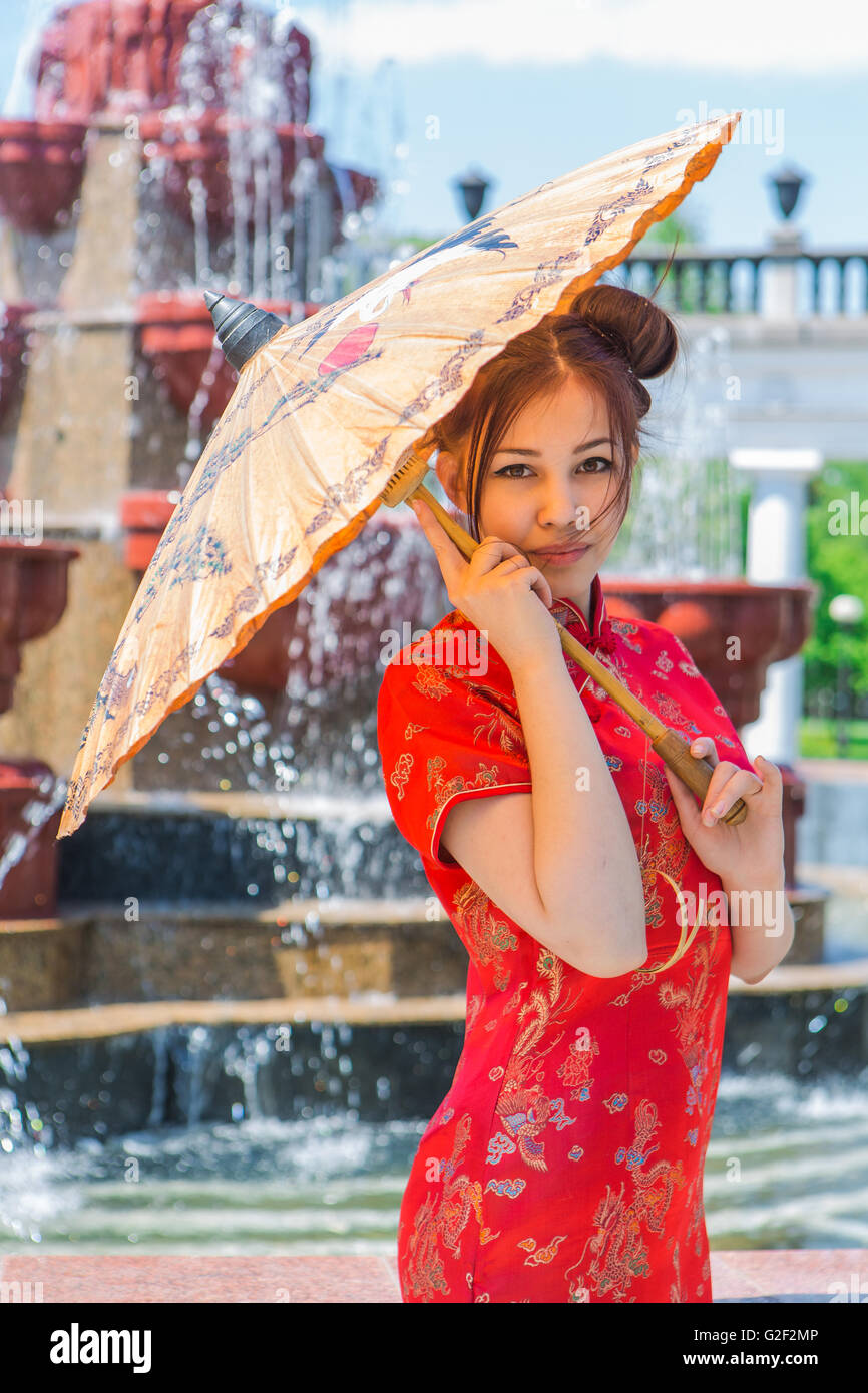 Hermosa muchacha asiática en chino tradicional vestido rojo con paraguas de  bambú cerca de Trevi Fotografía de stock - Alamy