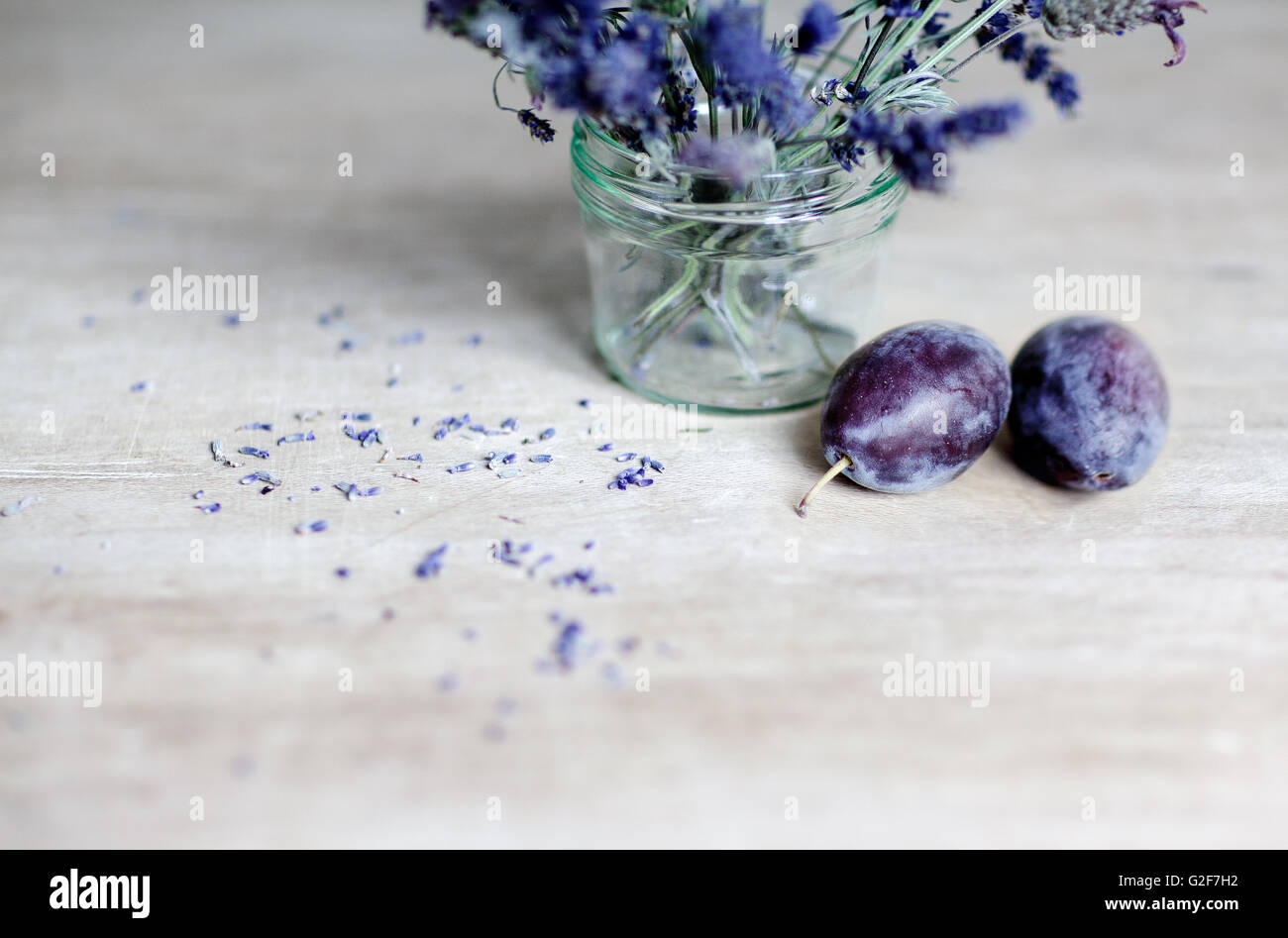 Ciruelas maduras frescas y glas con lavanda sobre mesa de madera Foto de stock