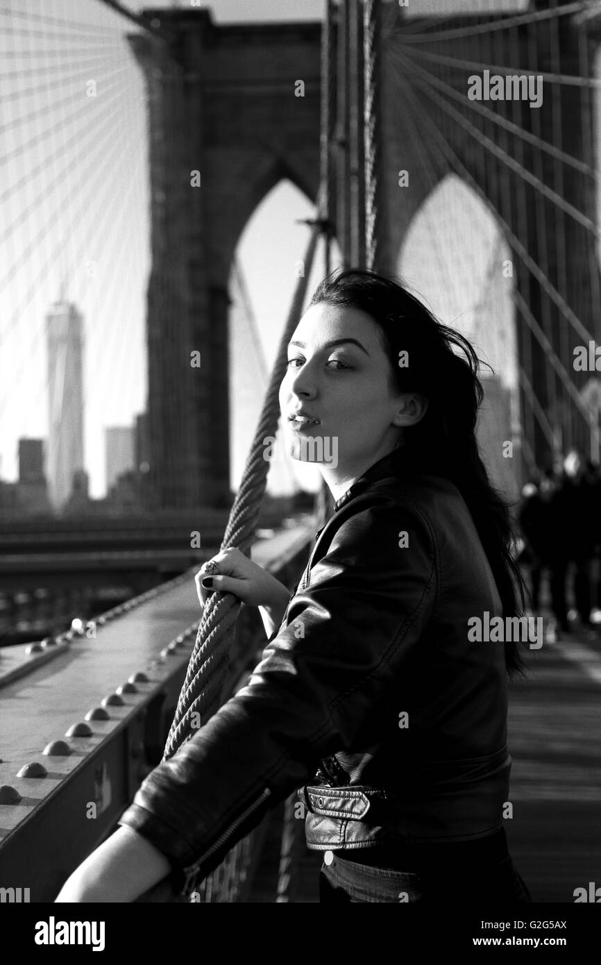 Joven Mujer adulta en el puente de Brooklyn mirando a la distancia, la ciudad de Nueva York, Nueva York, EE.UU. Foto de stock