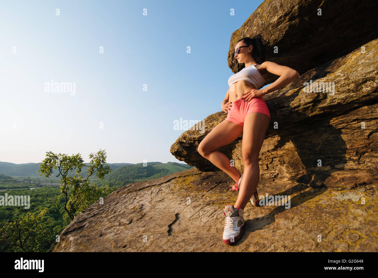 Longitud total retrato de una joven mujer atlética con perfecta figura  vestida en ropa deportiva en paisaje de montaña. Colocar saludable mujer  posando apoyándose en la roca Fotografía de stock - Alamy