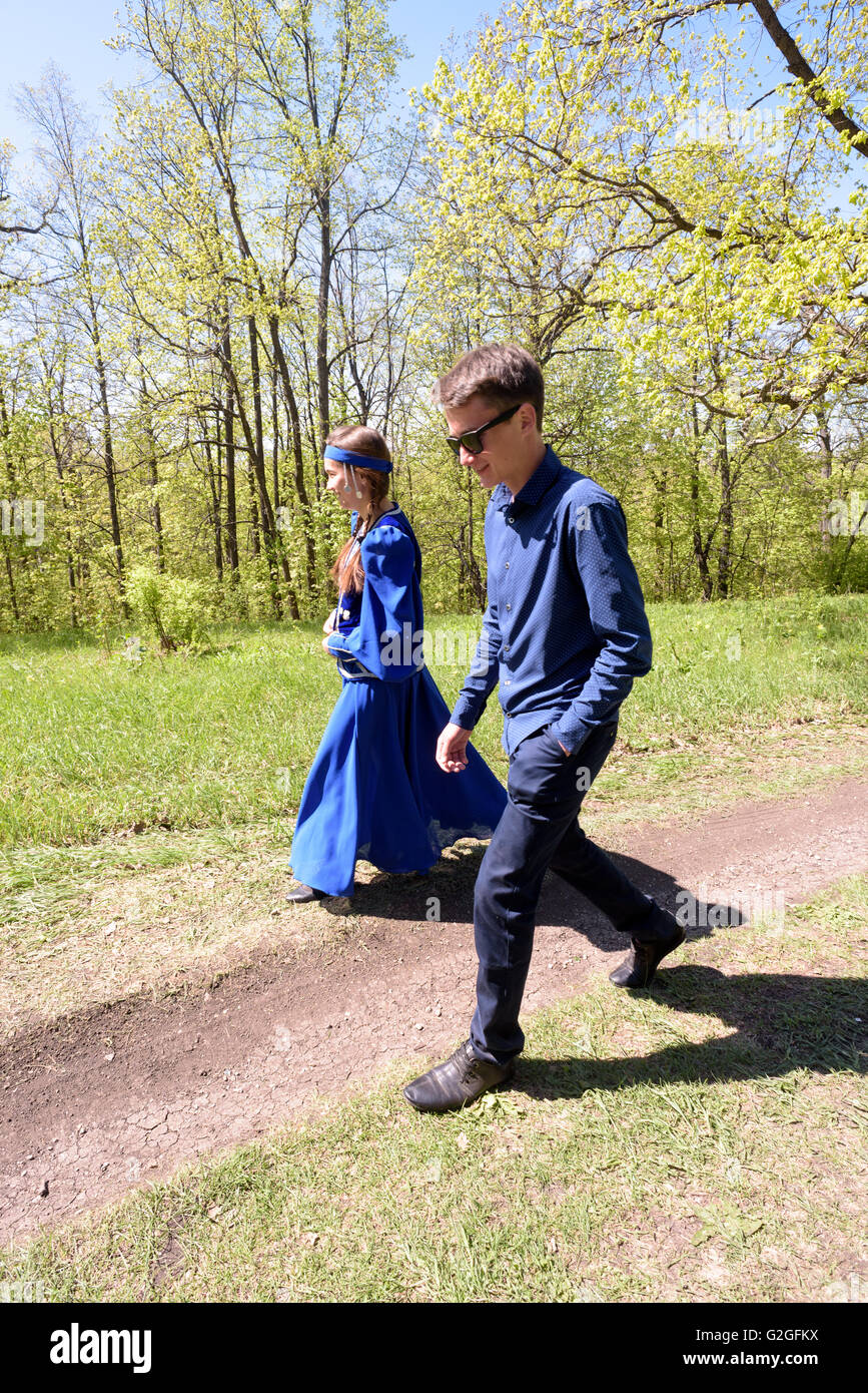 Chica joven rusa en traje azul tradicional de Rusia y un muchacho caminando  por un sendero a través de un bosque Fotografía de stock - Alamy