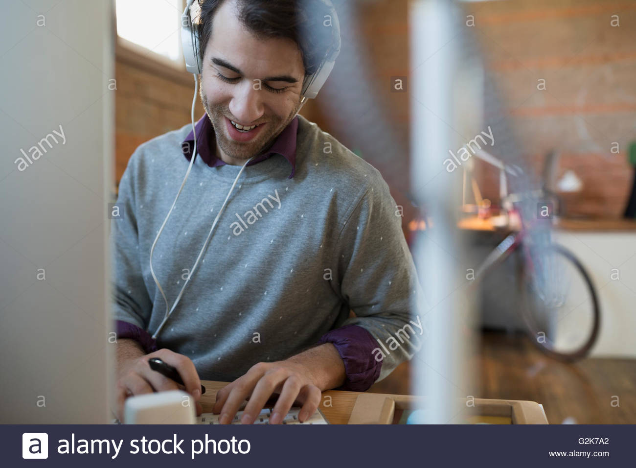 Diseñador sonriente con auriculares utilizando equipo de oficina Foto de stock