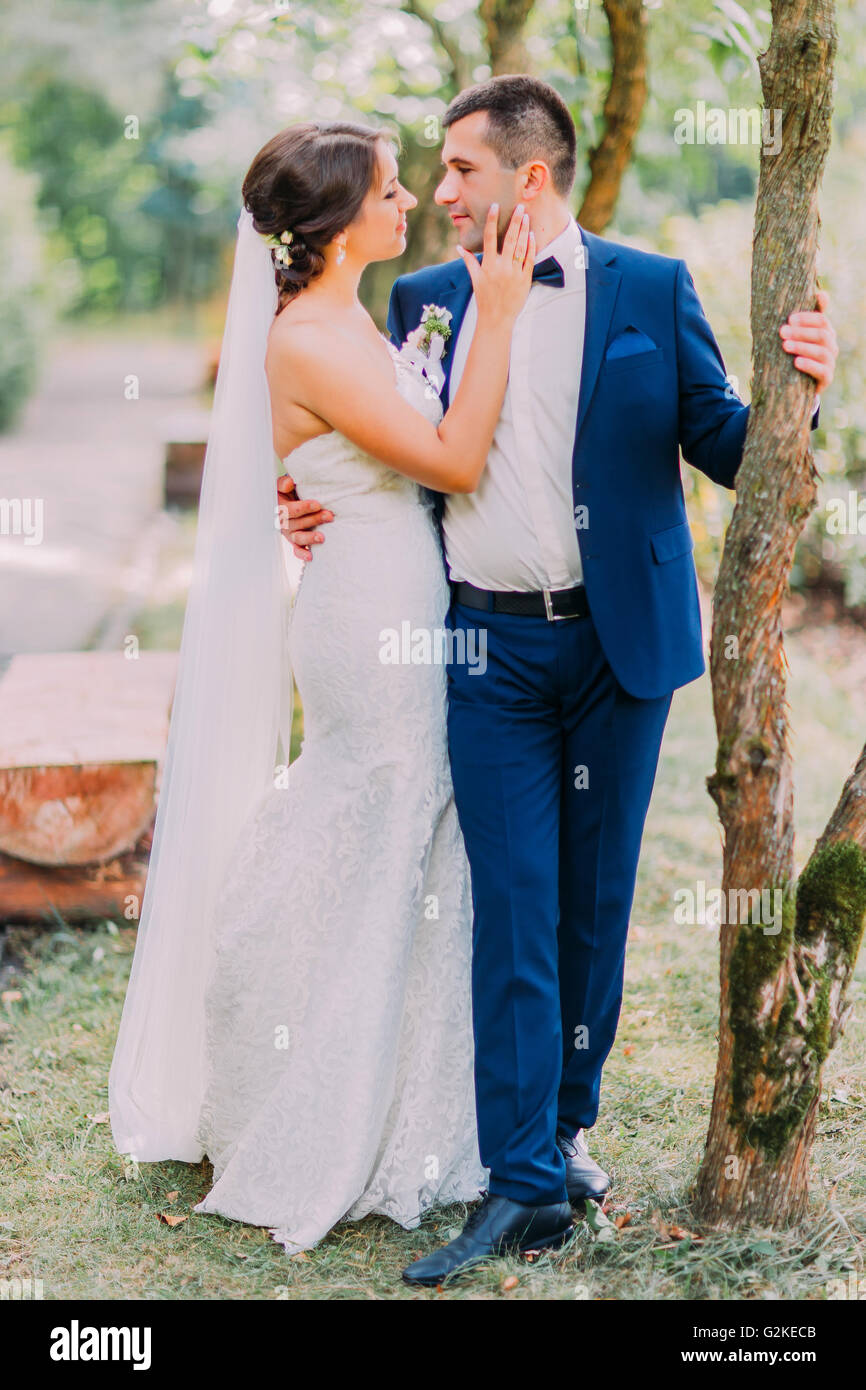 Elegante traje de novio en un lujoso sosteniendo su novia vestido blanco con largo en el exterior. Vista al parque está en segundo plano Fotografía de stock - Alamy