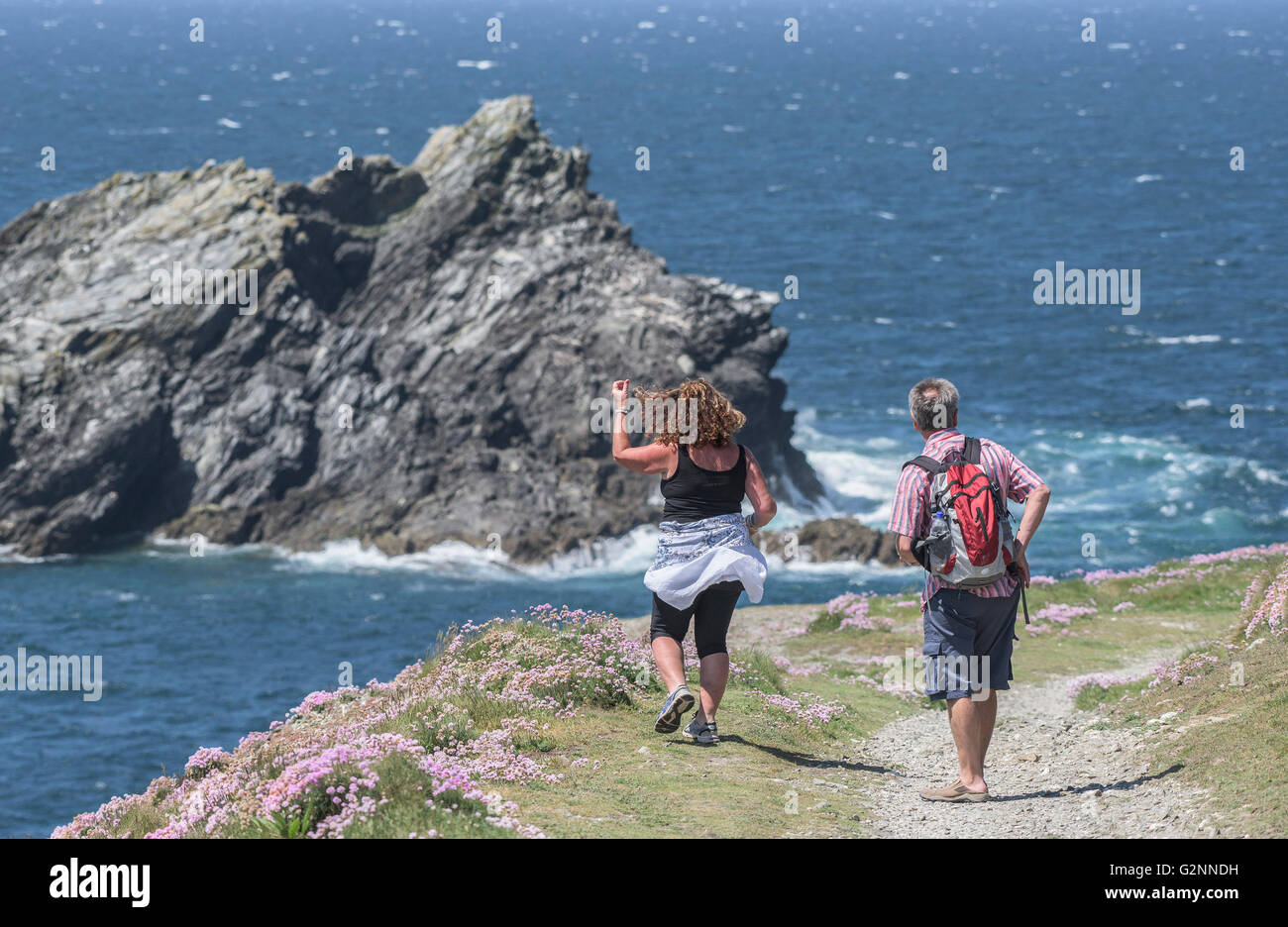 Tiempo soleado como los turistas disfrutan de un paseo en medio Pentire cabecero en Newquay, Cornwall. Foto de stock