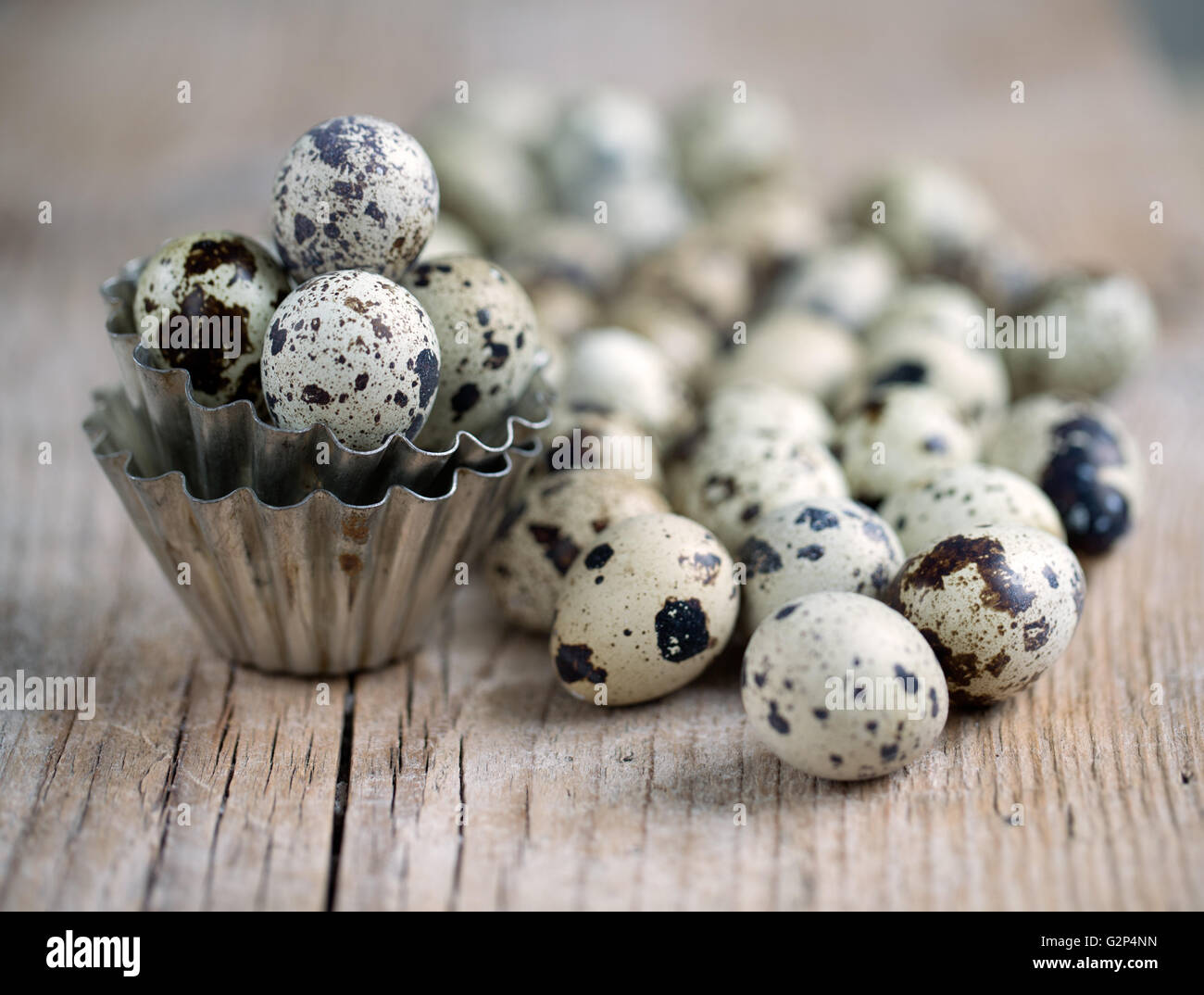 Huevos de codorniz con pequeñas formas de cocción de metal en la mesa Foto de stock