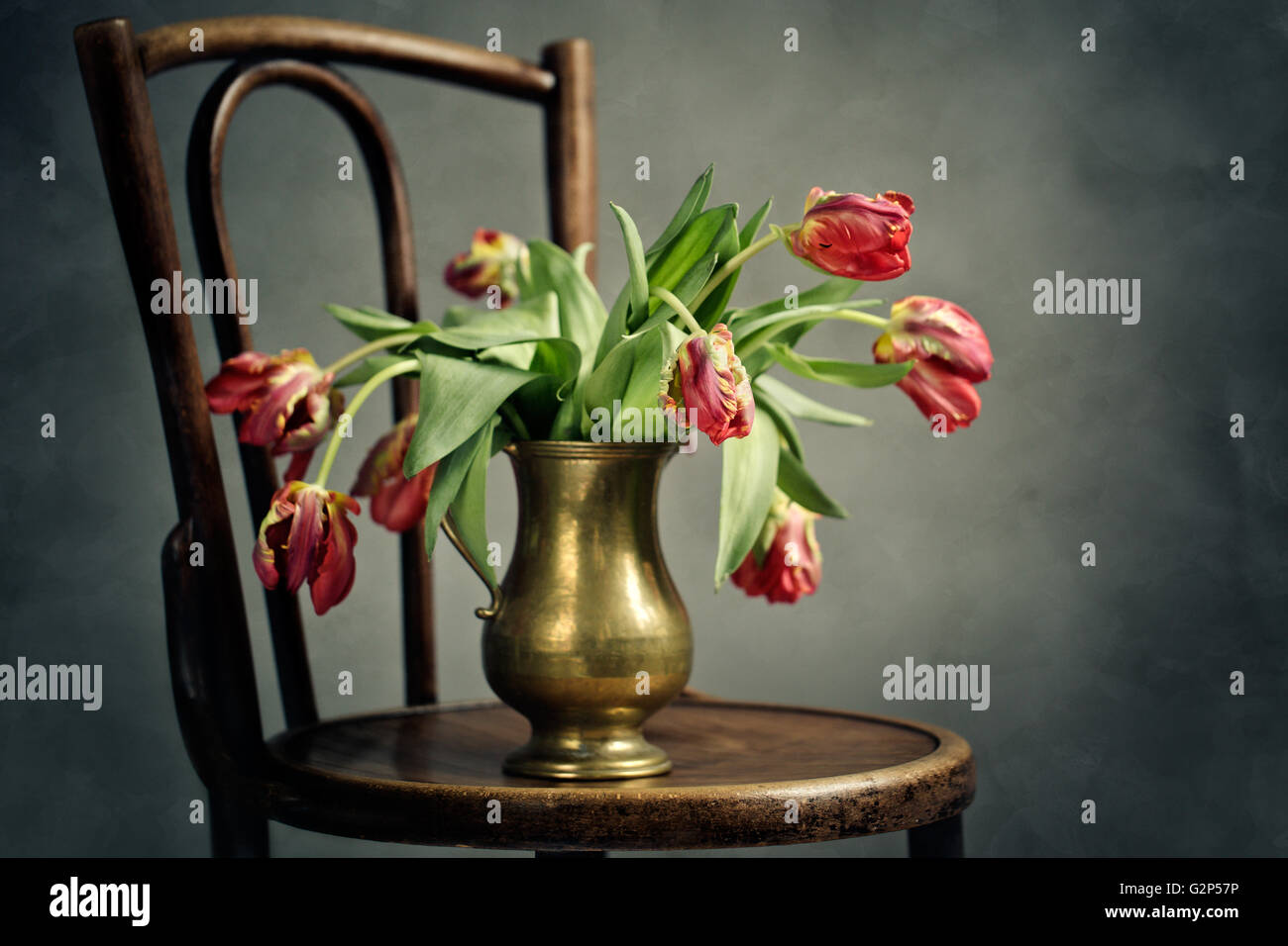 Bodegón con retro marchito tulipanes en florero de metal Foto de stock