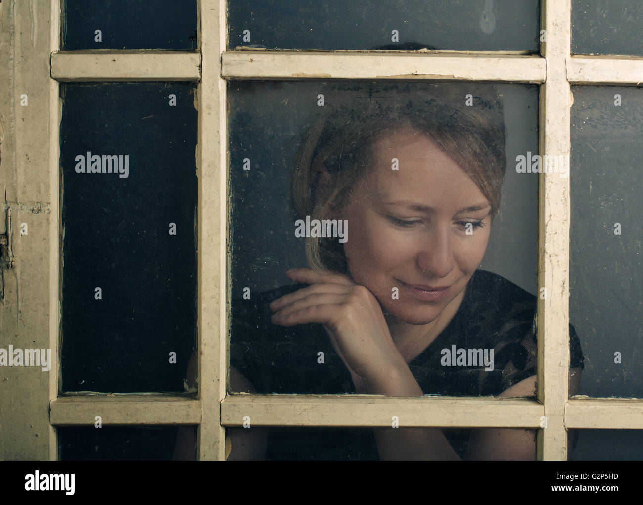 Retrato de una mujer adulta con blone vieja ventana rústica Foto de stock