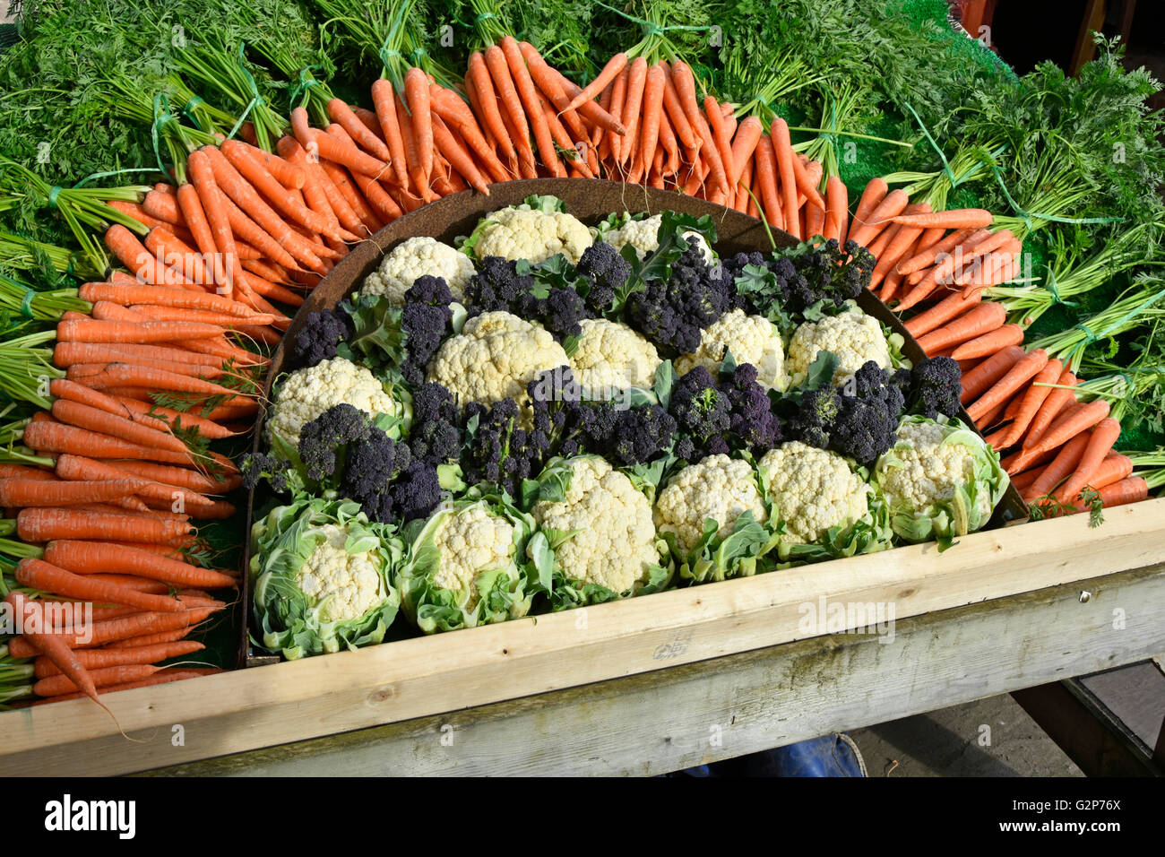 Las zanahorias coliflor, brócoli y organizarse como un día cinco coloridos vegetales display promocional en el carro fuera de la entrada a la tienda granja Essex, Inglaterra Foto de stock