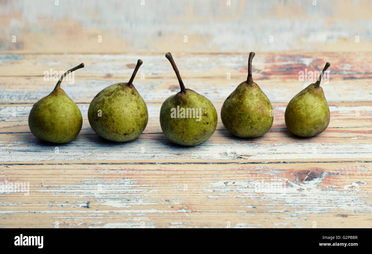 Cinco pequeñas peras verdes sobre la plancha de madera Fotografía de stock  - Alamy