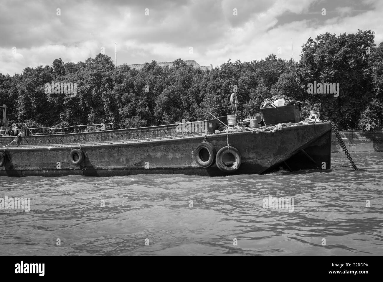 Imagen en blanco y negro de un oxidado en desuso barcaza en el río. Foto de stock
